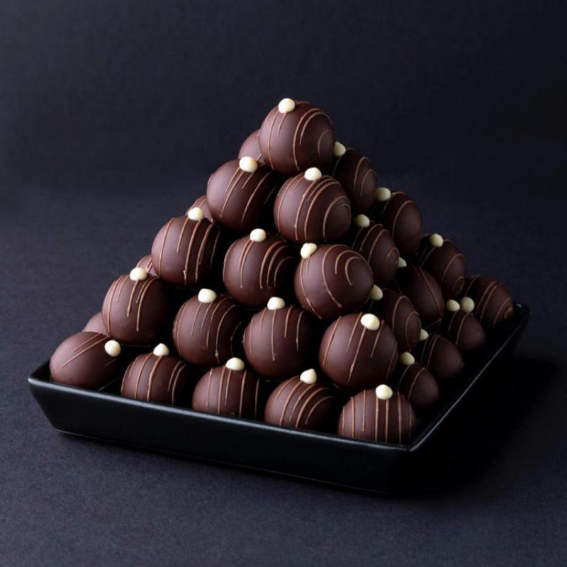 Pyramide aus handgemachten Herrentrüffeln mit dunkler Schokolade und feiner Dekoration – elegante Confiserie-Präsentation.