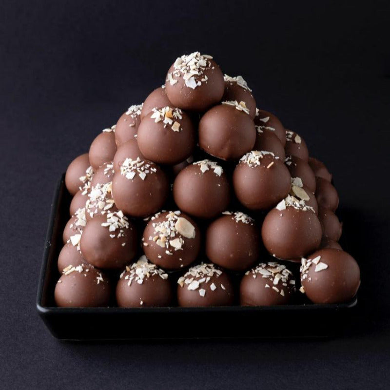 Handgemachte Calvados-Trüffel mit Vollmilchschokolade und Mandeln, dekorativ zur Pyramide geschichtet – edle Trüffelvariation.
